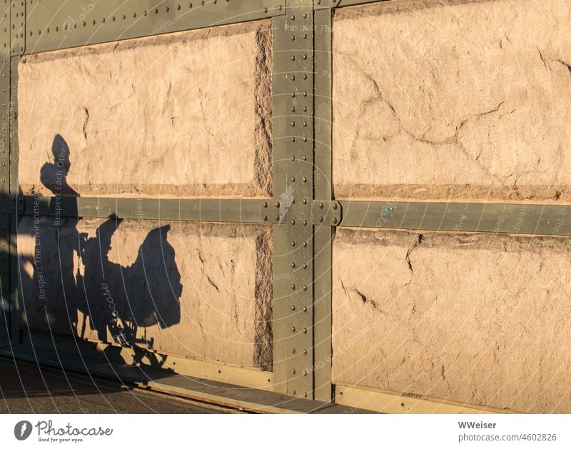 Der Schatten einer Mutter mit Kinderwagen auf einer sonnenbeschienenen alten Mauer Frau Kindheit laufen draußen spazieren Wand Sonne Licht Struktur Metall