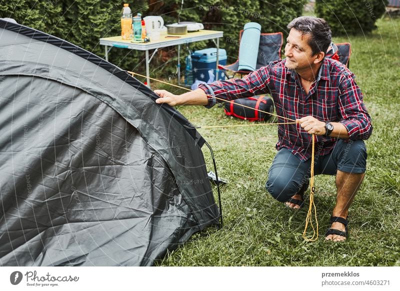 Mann, der ein Zelt auf dem Campingplatz während der Sommerferien aufbaut. Vorbereiten des Campingplatzes zum Ausruhen und Entspannen. Urlaub im Freien in der Nähe der Natur verbringen