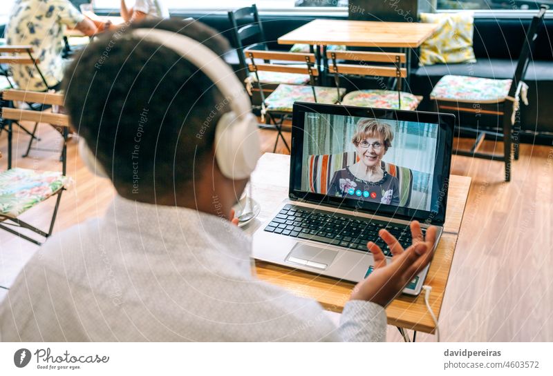 Mann spricht per Videoanruf mit seiner Mutter in einer Cafeteria unkenntlich sprechend Laptop Kantine Internet Kopfhörer Bildschirm Person Videokonferenz