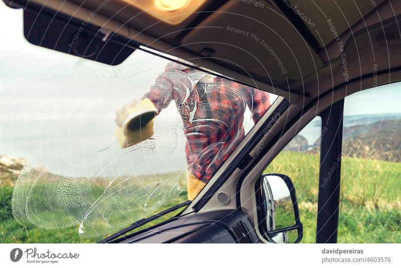Mann beim Reinigen der Windschutzscheibe eines Wohnmobils im Freien unkenntlich einseifend Glas Kleintransporter Schwamm Blick von innen durch das Glas