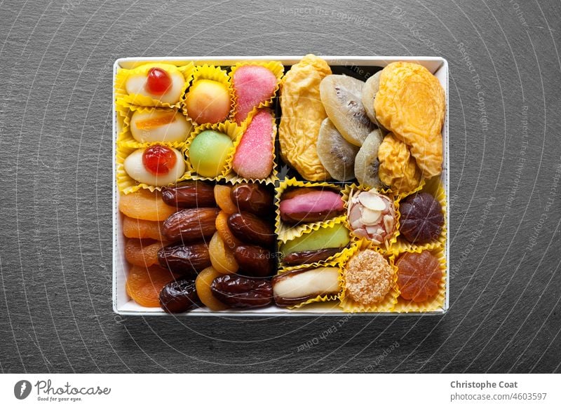 Schiefertablett mit einer weißen Metallschale mit Süßigkeiten und Trockenfrüchten in der Mitte. Studioaufnahme weiße Farbe voller Rahmen Food-Fotografie Tablett
