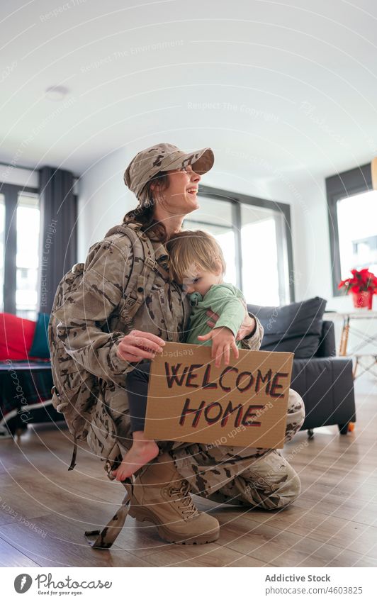 Zufriedene Militärfrau, die ihren Sohn mit einer Grußtafel umarmt Mutter Soldat Pflicht Junge Dienst ankommen Willkommen zu Hause Aufschrift Lächeln Patriotin