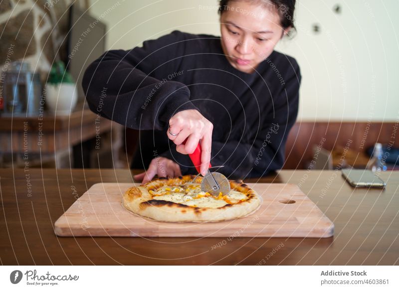 Asiatische Frau schneidet gebackene Pizza Koch Küche kulinarisch selbstgemacht geschnitten italienische Küche Kutter Küchenchef Tisch Licht Dame heimwärts