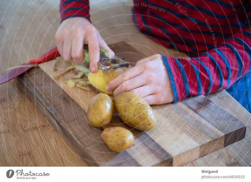 Kind schält in der Küche Kartoffeln Kochen bio slowfood gesund Gemüse Lebensmittel Erziehung Kinder Messer lecker