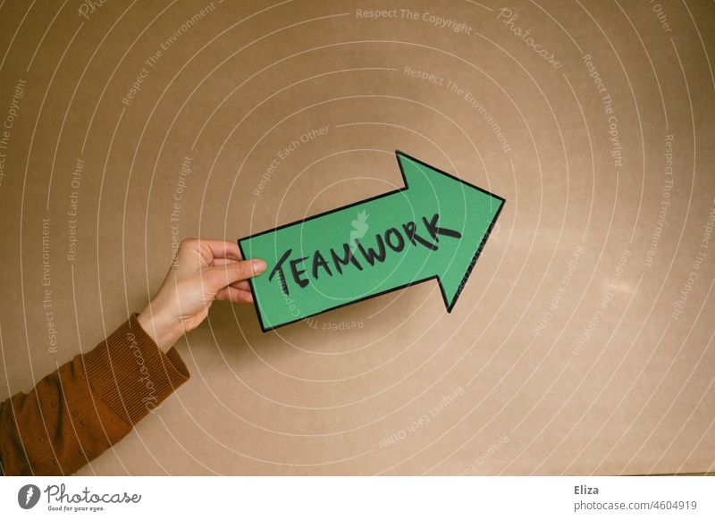 Frau hält einen grüne Pfeil auf dem Teamwork geschrieben steht Gruppenarbeit zusammen Arbeitswelt gemeinsam Teamgeist gemeinschaftlich Teambildung Erfolg