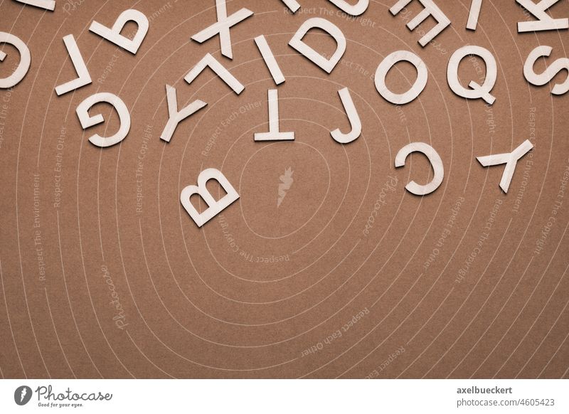 Durcheinander von Holzbuchstaben, die auf braunen Papierhintergrund herunterfallen Buchstaben fallend Hintergrund Design abstrakt Großbuchstaben Wirrwarr