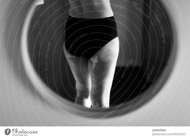 Rückansicht einer Frau in Unterwäsche im Spiegel. Schwarzweiß Aufnahme.  Beine und Po. Body Positivity frau körper nackt unterwäsche slip unbekleidet spiegel
