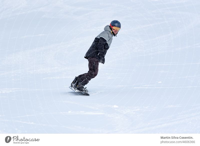 Junger Mann beim Snowboarden auf den Pisten eines Skigebiets. Aktion aktiv Aktivität Erwachsener Hintergrund blanko blau Holzplatte Bekleidung kalt cool bergab