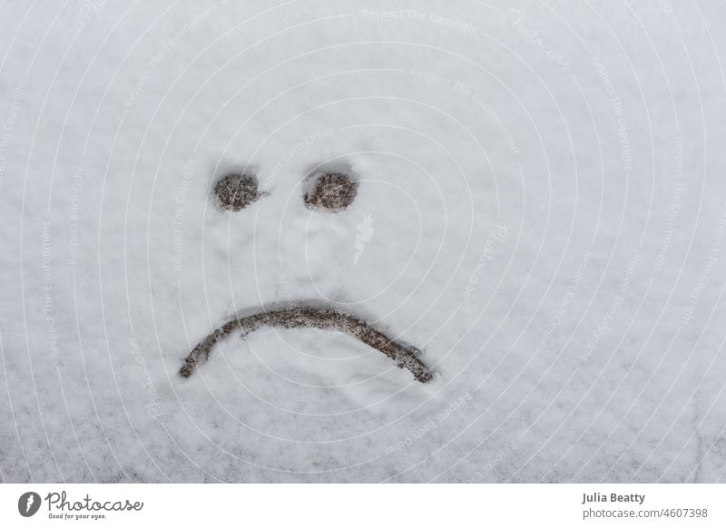 Trauriges Gesicht nach leichtem Schneefall auf den Boden gezeichnet; vom Sommer träumend trauriges Gesicht Emoji Stirnrunzeln Gesicht verziehen Skizze Zeichnung