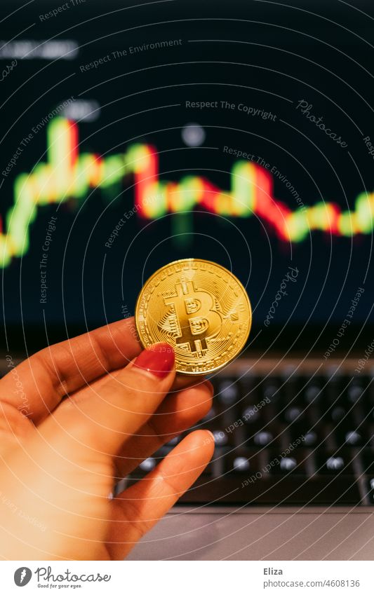 Frau hält eine Bitcoin-Münze. Im Hintergrund sind Handelskerzen auf einem Bildschirm. Kryptowährungen. Bitmünze Kerzen Preis Grabgewölbe Geld Kapitalwirtschaft
