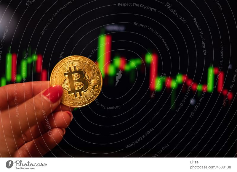 Frau hält eine Bitcoin Münze. Im Hintergrund sind Trading Kerzen auf einem Bildschirm. Kryptowährungen. Kurs Kryptokurs Geld Handeln Kapitalwirtschaft Finanzen