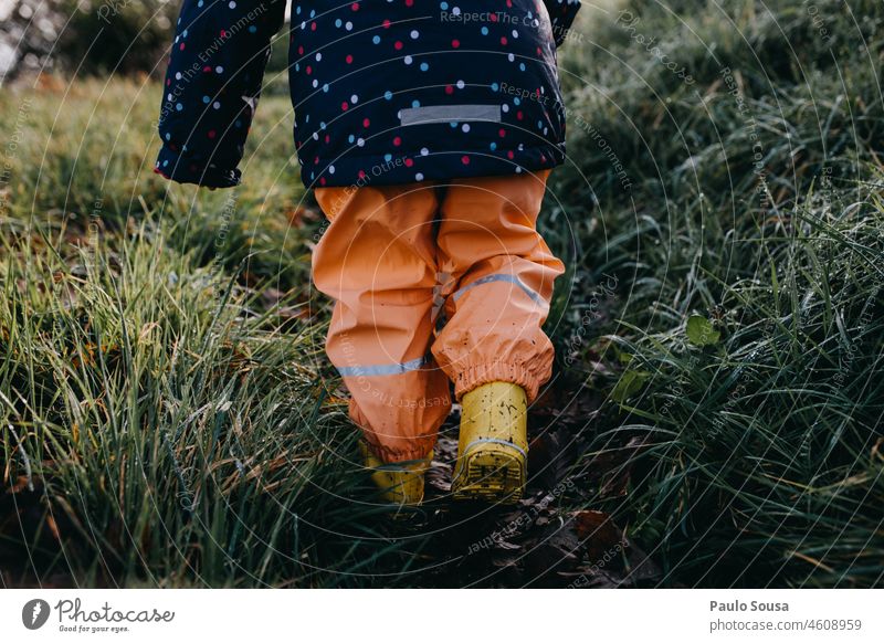 Rückansicht Kind mit gelben Gummistiefeln Kindheit Winter Regen Gras Wetter Genuss im Freien Wasser Außenaufnahme nass Stiefel Freude Fröhlichkeit mehrfarbig