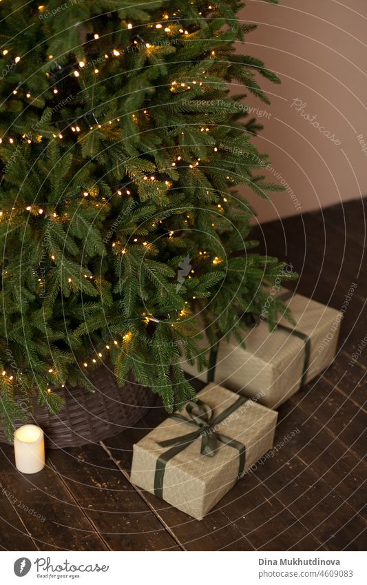 Eingepackte Geschenke unter dem minimalistischen Weihnachtsbaum mit festlichen Lichtern. Minimal neutralen Farben Urlaub Gruß Postkarte. Weihnachten