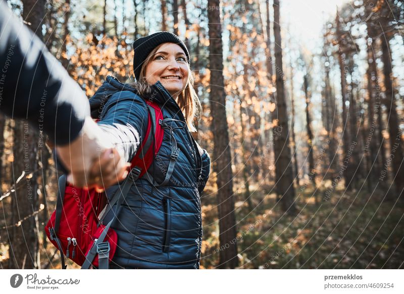 Paar hält sich an den Händen und genießt die Reise am Urlaubstag. Wanderer mit Rucksäcken zu Fuß auf Waldweg an einem sonnigen Tag Ausflug wandern Abenteuer