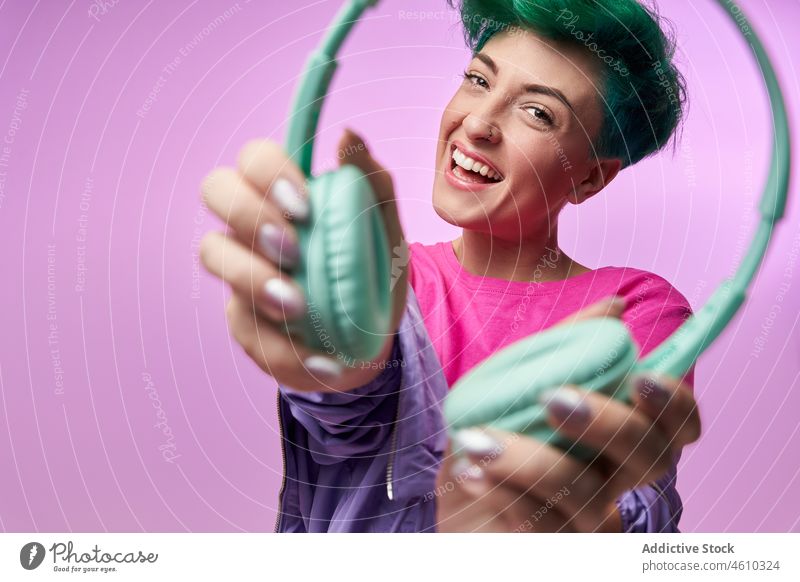 Genießen Sie Frau in bunten Retro-Kleidung zeigt Kopfhörer meloman Stil tausendjährig 80s Mode Design retro Musik Atelier grünes Haar Model Kurze Haare