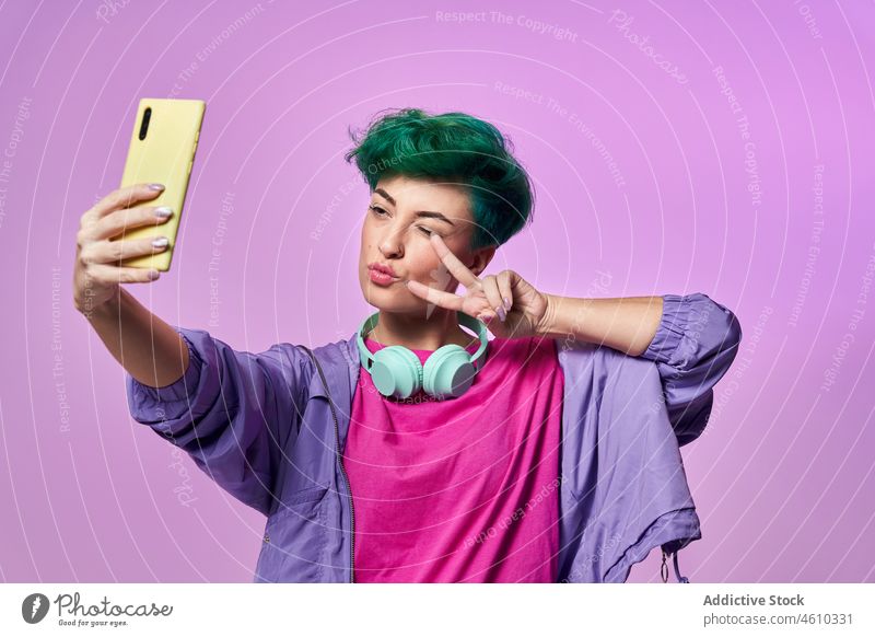 Fröhliche Millennial-Frau macht Selfie Smartphone Selbstportrait soziale Netzwerke Kopfhörer meloman Stil tausendjährig 80s Mode Design retro Atelier