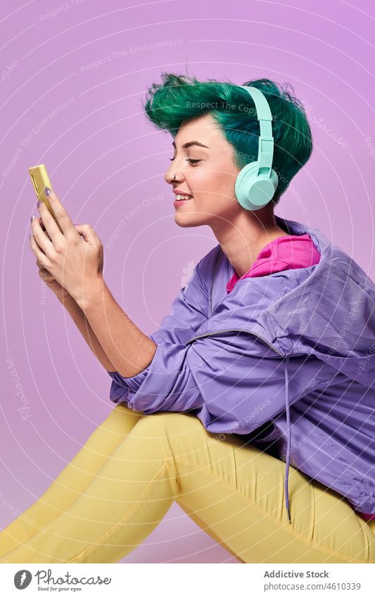 Millennial-Frau mit Kopfhörern beim Surfen auf dem Smartphone Browsen soziale Netzwerke meloman Stil tausendjährig 80s online Mode Design retro Musik Atelier