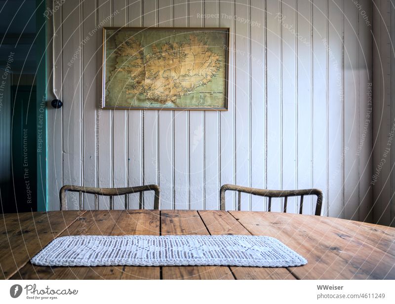 In diesem traditionellen isländischen Haus hängt eine Karte von Island an der Wand, auf dem Tisch liegt ein Häkeldeckchen Stühle Zimmer Raum still ruhig
