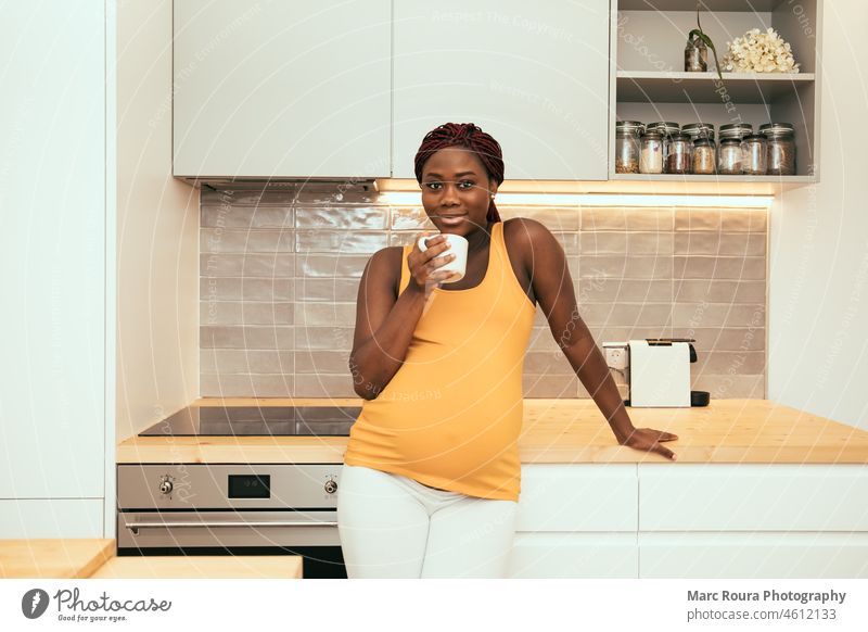 schwarze schwangere Frau, die in der Küche eine Tasse Kaffee trinkt Erwachsener Afrikanisch Appartement Aroma schön Getränk Pause Frühstück Helligkeit