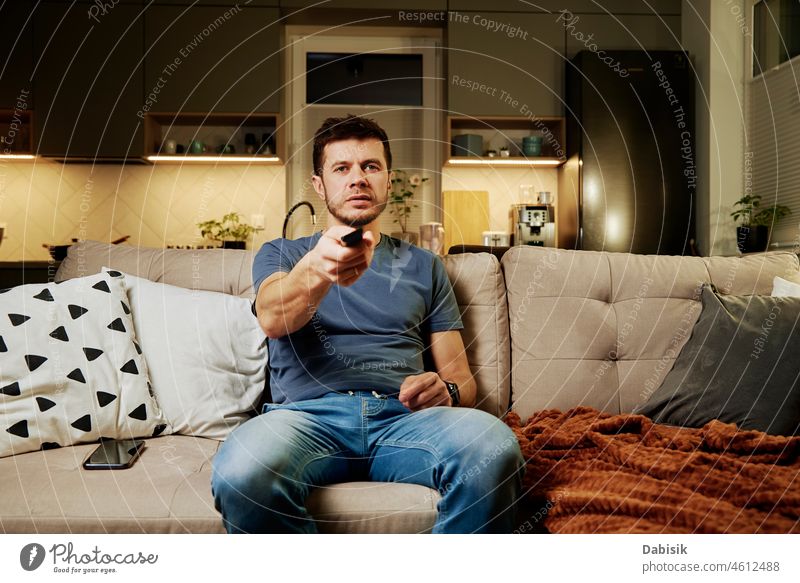 Mann benutzt Fernbedienung, um fernzusehen verwenden zuschauend FERNSEHER Sofa Wohnzimmer Schalter Liege im Innenbereich ruhen Haustier LAZY Freizeit Wochenende
