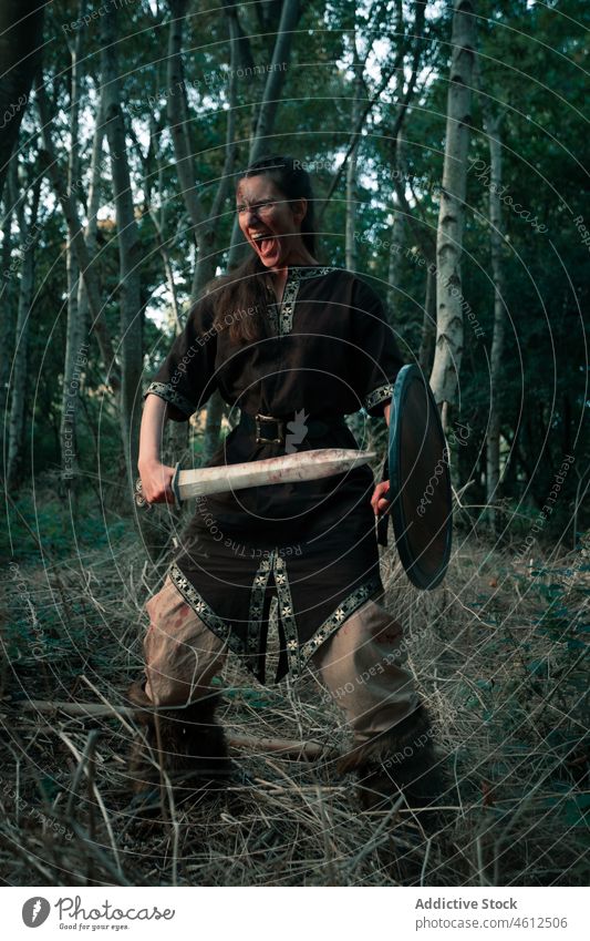 Wütende Wikingerin mit Waffe und Schild bei der Rekonstruktion einer Schlacht Frau attackieren Krummdolch Schutzschild angriffslustig schreien Nachstellung