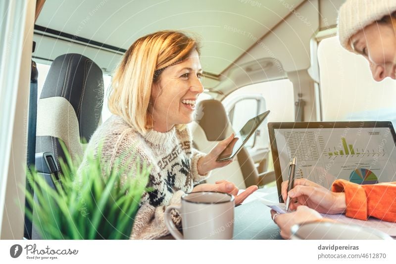 Lachende Frauen bei der Telearbeit in einem Wohnmobil Laptop schreibend Kleintransporter Ausflug Glück abgelegen Arbeit Menschen Tabelle Job arbeiten Business