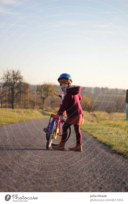 Mädchen wartet das sie los fahren kann mit ihrem Fahrrad Herbst herbstlich Straße Helm Fahrradfahren Oldschool Fahrradhelm ökologisch Stiefel Mütze Landschaft