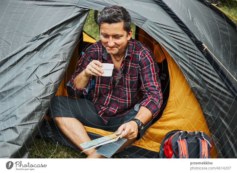 Mann entspannt sich im Zelt beim Camping im Sommerurlaub. Mann hält Karte bei der Planung der nächsten Reise Urlaub Ausflug Abenteuer Campingplatz reisend Lager