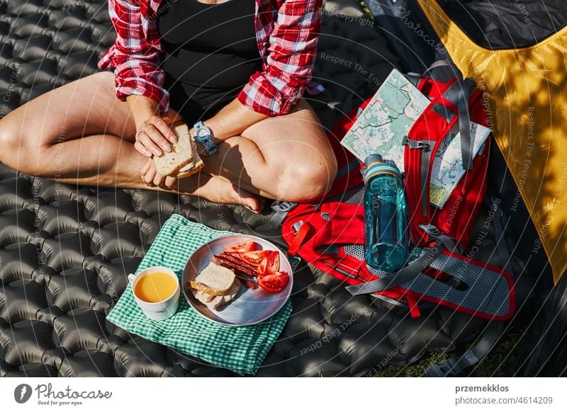 Frau frühstückt beim Zelt auf dem Campingplatz. Weibliche aktiv verbringen Sommerferien in der Nähe der Natur im Freien Urlaub Ausflug Abenteuer Frühstück