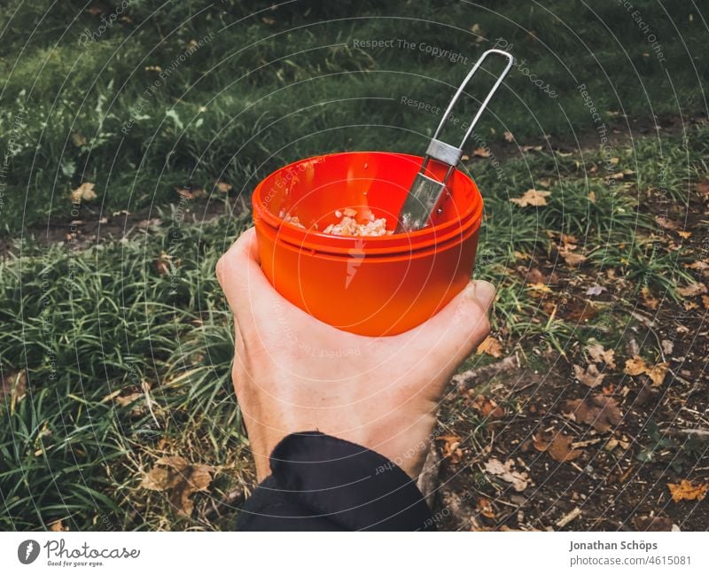 Müsli Becher mit Klapplöffel auf einer Waldwanderung Müslibecher Büchse Aufbewahrung Essen Mahlzeit draußen Outdoor Wanderung Proviant Wandern rot Hand halten