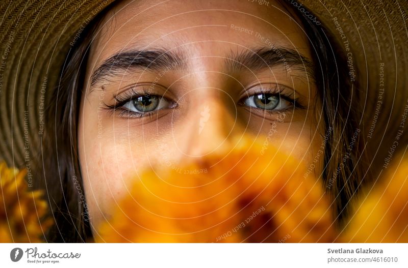 Closeup Porträt schöne Augen der lateinamerikanischen Mädchen in Strohhut mit braunen Haaren Gesicht mit orangefarbenen Blumen Chrysanthemen bedeckt Frau