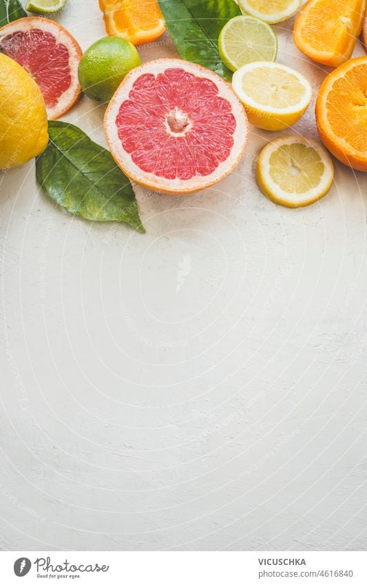 Zitrusfrüchte Hälften Hintergrund auf weißem Tisch: Grapefruit, Orange, Limette und Zitrone. Gesunde Vitamin-C-reiche Früchte mit grünen Blättern. Draufsicht mit Kopierbereich.