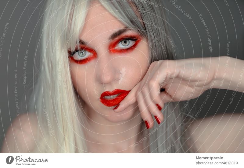 rot geschminkte Frau mit weiß-grauen Haaren grauhaarig jung weißhaarig blond Haarfarbe Frisur hübsch schön Gesicht Schminke rote Nägel roter Lippenstift