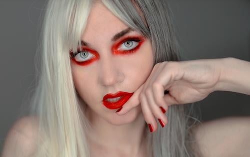 rot geschminkte Frau mit weiß-grauen Haaren grauhaarig jung weißhaarig blond Haarfarbe Frisur hübsch schön Gesicht Schminke rote Nägel roter Lippenstift