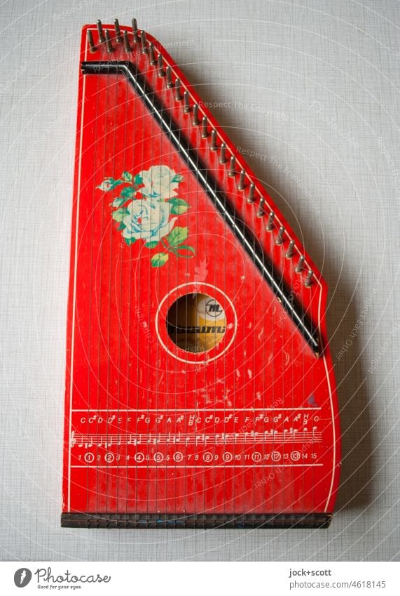 rote Harfe mit Tonleiter und floralen Muster verziert Kinderharfe Instrument Musikinstrument Detailaufnahme lackiert Holz retro Tischplatte gebraucht DDR Zither