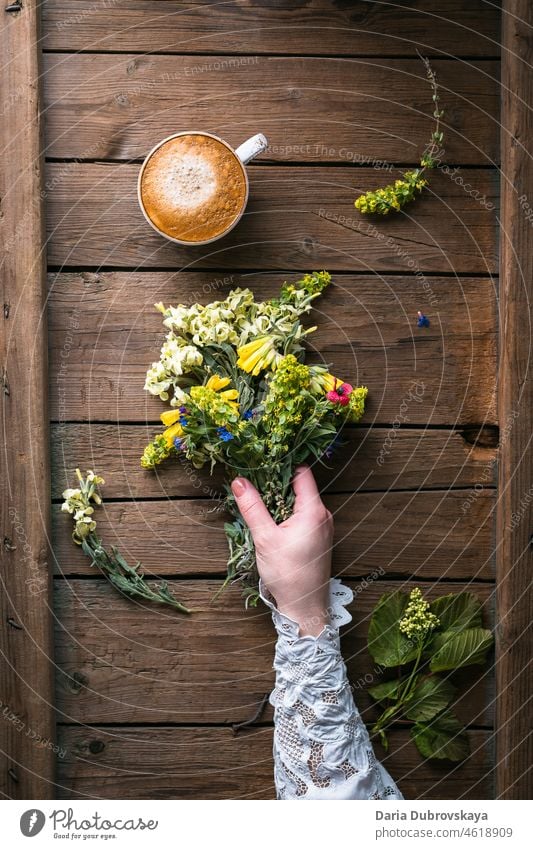 Ein Strauß Wildblumen in einer Frauenhand und eine Tasse Kaffee Kaffeepause Konzept Lifestyle Nahrungssuche Futter Sommer Versammlungen schön rustikal Stimmung