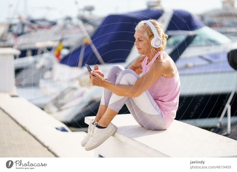 Reife sportliche Frau, die eine Pause macht, um eine Fitness-App auf ihrem Smartphone zu überprüfen reif aussruhen Senior Kalorien aktiv Training Läufer Person