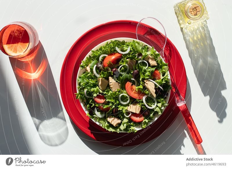 Thunfischsalat mit Zwiebeln und Tomaten, serviert auf roten Tellern Salatbeilage Olivenöl Servieren mediterran Blatt Rezept organisch grün Ernährung Löffel