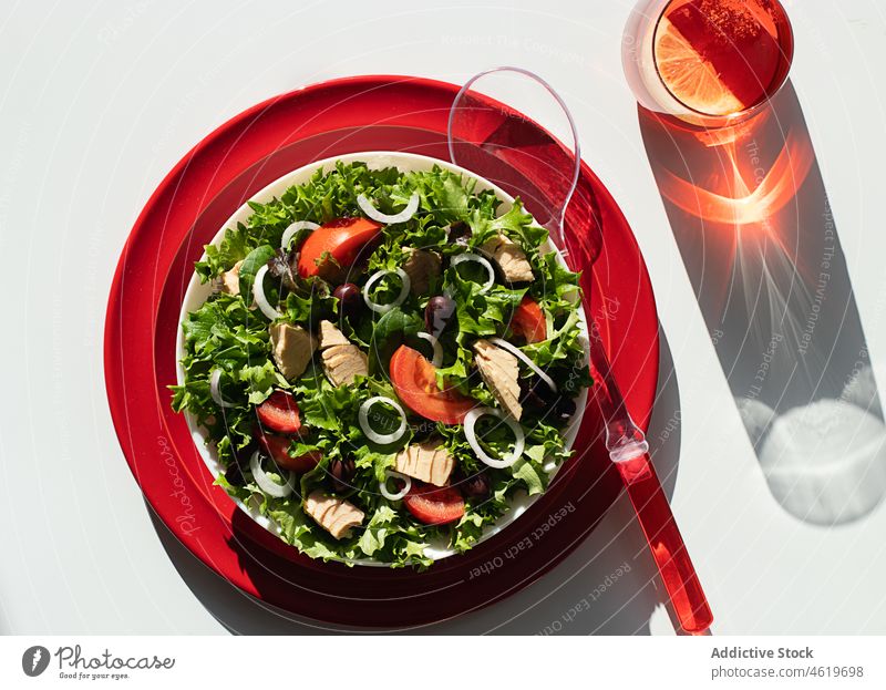 Thunfischsalat mit Zwiebeln und Tomaten, serviert auf roten Tellern Salatbeilage Olivenöl Servieren mediterran Blatt Rezept organisch grün Ernährung Löffel