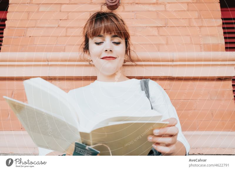 Junge Frau auf weißem Hemd hält und liest ein Buch auf dem Bahnhof, Lesen überall Menschen, Buch Hobby-Fan. Warten auf den Zug zu kommen, Tötung Freizeitaktivitäten und Gewohnheiten