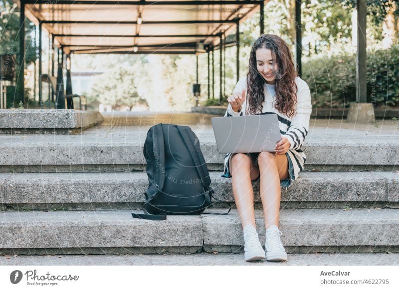 Junger arabischer afrikanischer Student überprüft seinen Laptop an der Universität im Freien während einer Pause in den Klassen, Sonnenuntergang Umgebung. Neue Studienkurs, Selbstverbesserung und Lernen beim Lesen.