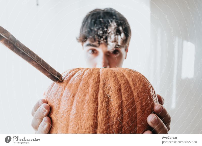 Junger Mann hält auf seine Hände eine super texturierte Kürbis mit einem Messer immer bereit für Halloween. Arbeit und manuelle Aktivitäten zu Hause, Party zu Hause Konzept. Close up Bild lustig glücklich Bild