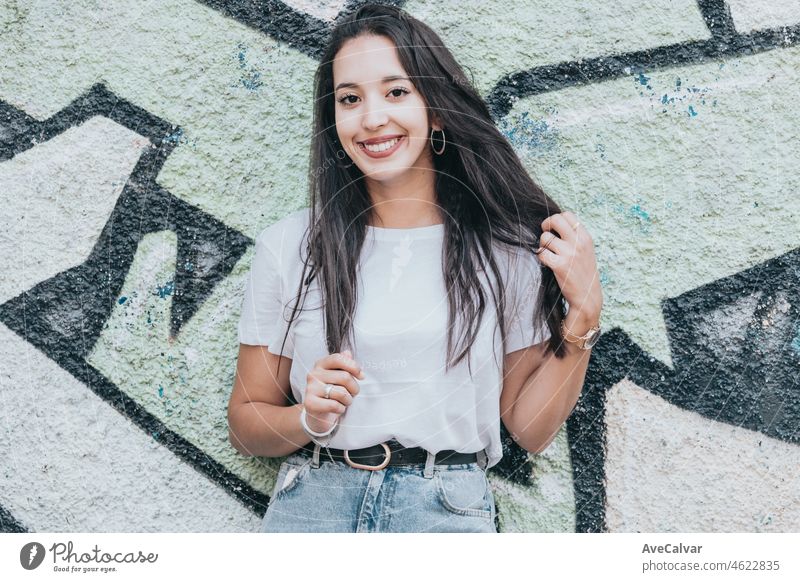 Porträt eines jungen arabischen afrikanischen Mädchens auf lächelnden Hip-Hop-Youngster-Attitüde suchen ernst in die Kamera auf einem weißen T-Shirt mit einem Graffiti-Hintergrund. Soziales Netzwerk-Modell-Konzept, Foto wie soziale teilen