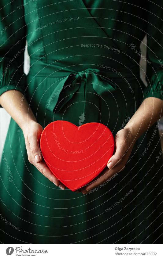Die Hände einer Frau halten ein rotes Herz. Valentinsgruß präsentieren Geschenk Beteiligung Hand Geben Liebe grün Kleid Smaragd Feiertag Überraschung Almosen