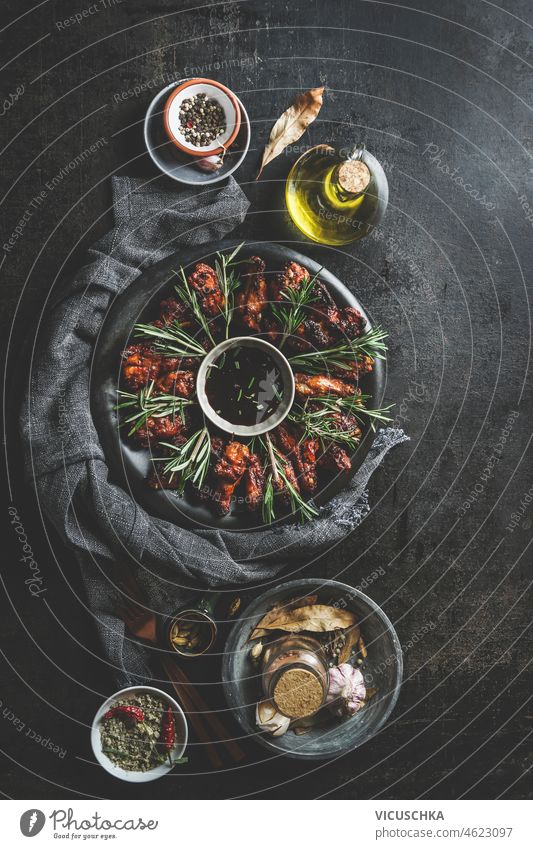 Teller mit gebratenen Hähnchenflügeln mit Kräutern und BBQ-Sauce auf dunklem rustikalem Hintergrund dunkel Küchenkräuter Gewürze Draufsicht Bestandteil lecker