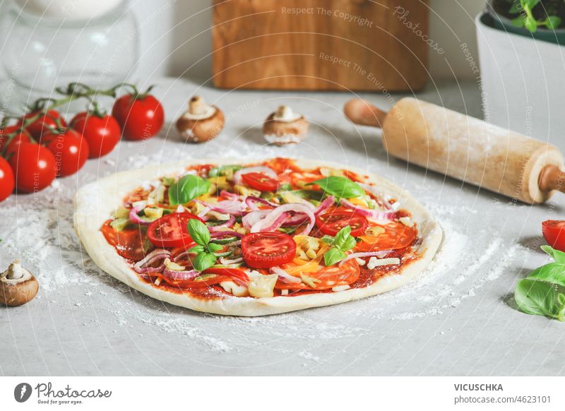 Hausgemachte Pizza auf hellem Tisch mit Nudelholz und Zutaten, Ansicht von oben selbstgemacht Vorbereitung Licht Draufsicht rot Gemüse Mittagessen Küche