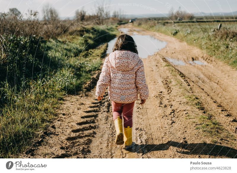 Rückansicht Mädchen zu Fuß auf schmutziger Straße Kind Kindheit 3-8 Jahre Außenaufnahme Farbfoto Mensch dreckig Kindheitserinnerung 1 Natur Fröhlichkeit Freude