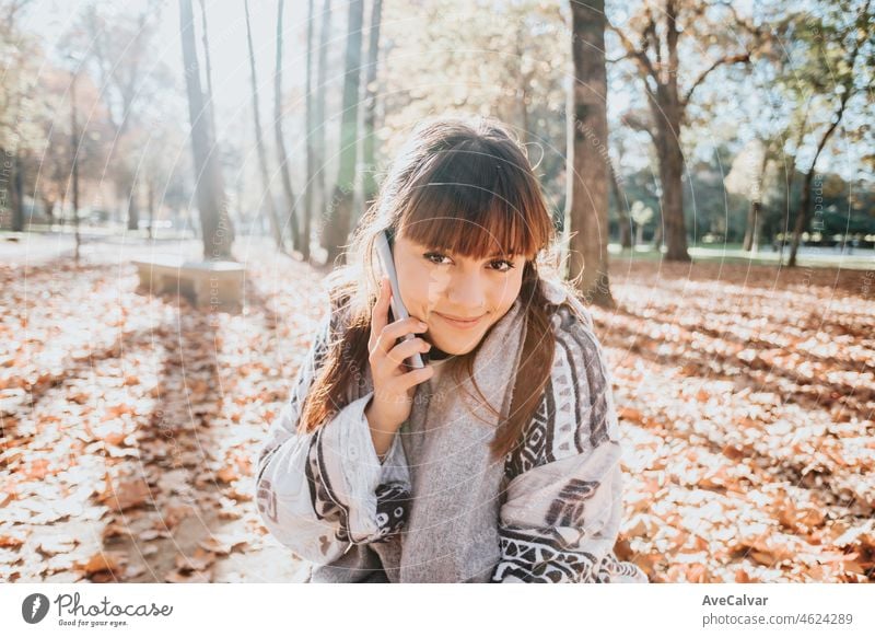 Junge Frau, die einen Spaß Anruf während eines Sonnenuntergangs im Wald während eines herbstlichen Wintertag. Konnektivität und soziales Konzept.Junge Menschen Lebensstil. Gruß Freunde online. Kopieren Raum.