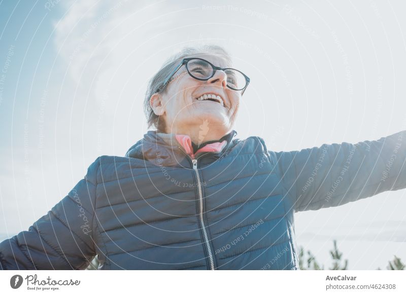 Close up Porträt eines super glücklich lächelnde alte Frau während eines Spaziergangs, tun Übung und Aktivitäten während des dritten Alters. Winken Arme mit Glück. Gesundheitspflege für Senioren und Natur Sport Oma