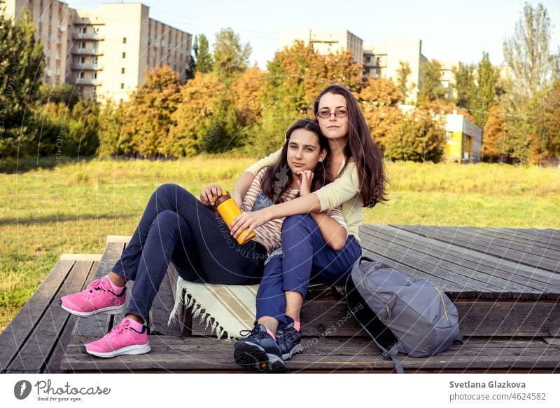 Zwei brünette Mädchen glückliche Familie Mutter und Tochter verbringen Zeit ruhen zusammen im Herbst Park Spaß haben, lächelnd, umarmen Mentale Gesundheit Entspannen Sie sich auf die Natur